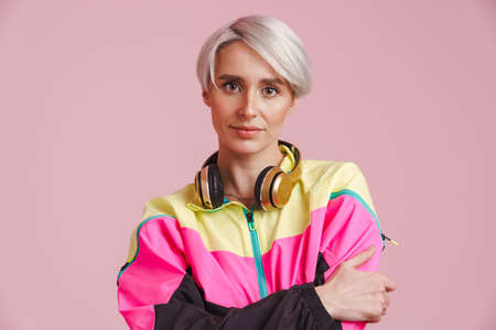 Young grey woman with headphones posing and looking at camera isolated over purple backgroundの写真素材