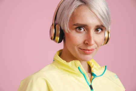 Young smiling woman listening music with headphones isolated over purple backgroundの写真素材