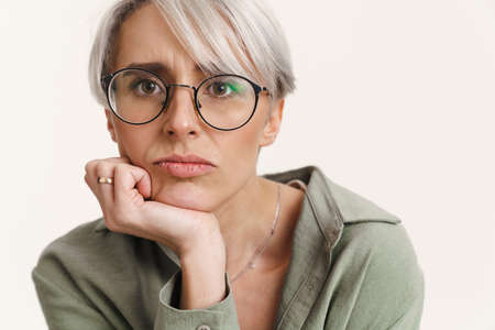 Young displeased woman in eyeglasses posing and looking at camera isolated over white backgroundの写真素材