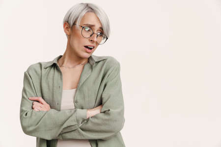 Shocked beautiful silver girl in eyeglasses looking aside isolated over white backgroundの写真素材