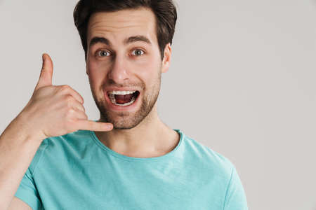 Excited handsome guy showing handset gesture and talking isolated over white background