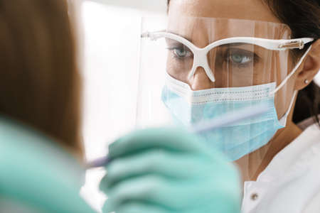 Mid aged female dentist examining patients teeth, close up