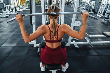 Caucasian athletic sportswoman doing exercise with fitness equipment while working out in gym
