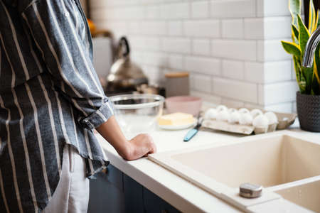 Caucasian young woman making pancake dough at home kitchen
