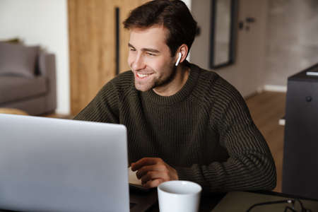 Smiling mid aged man working on laptop computer from home