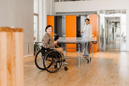 White woman in wheelchair playing  with her colleague at office