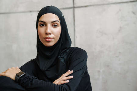 Young muslim woman in hijab posing and looking at camera indoorsの写真素材