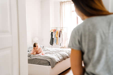 White woman looking at her daughter with down syndrome in bedroom at homeの写真素材