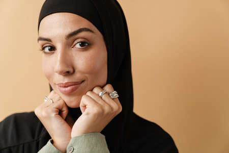 Young muslim woman in hijab unrolling fitness mat indoors