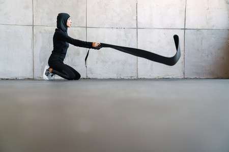 Young muslim sportswoman in hijab doing exercise while working out indoors