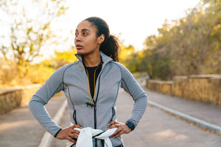 Focused african american sportswoman standing while working out in parkの写真素材