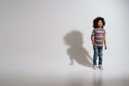 Happy preschooler african boy standing over white wall, having fun, full lengthの写真素材
