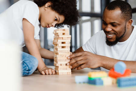 Black father and son playing with planks together at homeの写真素材