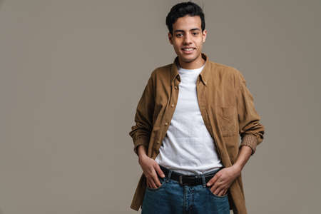 Brunette hispanic man in shirt smiling and looking at camera isolated over grey backgroundの写真素材
