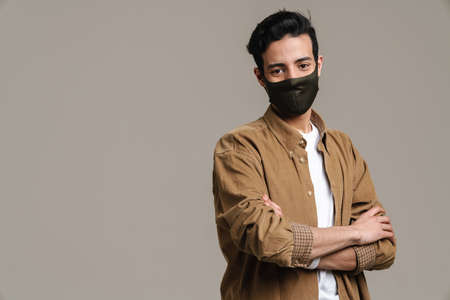 Brunette hispanic man in face mask looking at camera isolated over grey backgroundの写真素材