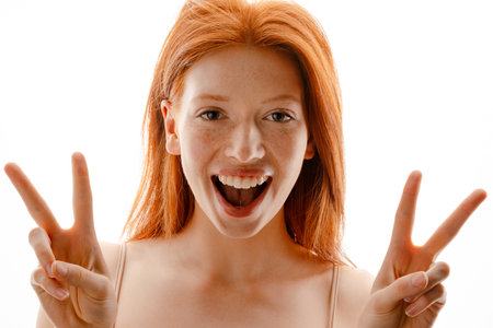 Portrait of a happy young redhead woman with healthy freckled skin posing isolated over white,...