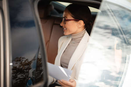 Image of a beautiful positive pleased business woman sitting in a carの写真素材