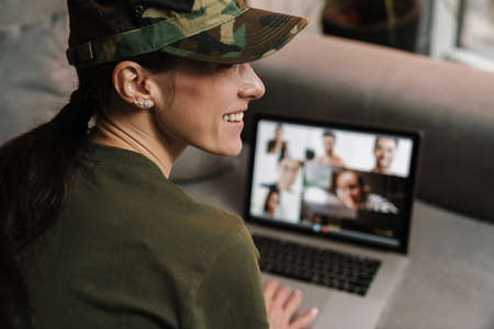 Happy soldier woman smiling while making conference call on laptop indoors