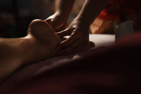 Professional masseuse doing foot massage with oil in spa indoorsの写真素材