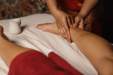 Professional masseuse doing foot massage with oil in spa indoorsの写真素材