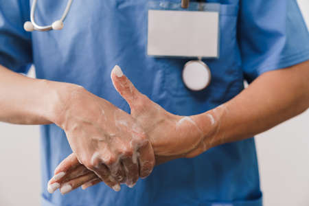 Close up of a female doctor washing her hands with soap isolated over white backgroundの写真素材