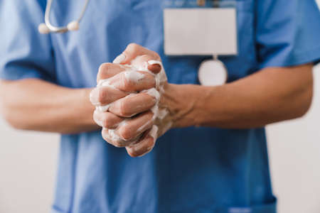 Close up of a female doctor washing her hands with soap isolated over white backgroundの写真素材