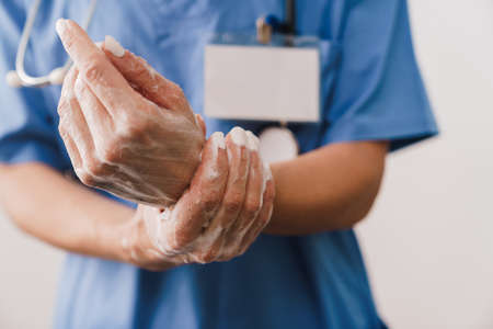 Close up of a female doctor washing her hands with soap isolated over white background