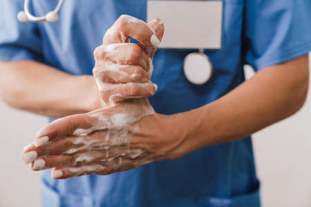 Close up of a female doctor washing her hands with soap isolated over white background