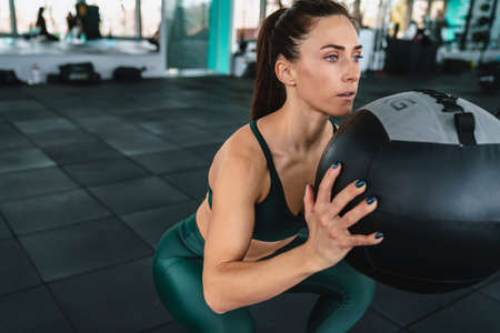 White sportswoman doing workout with medicine ball in gym