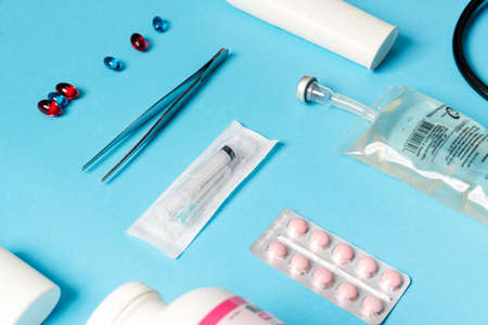 The close-up shot of a medical instruments consisting of tweezers, syringe, pills, liquid container...