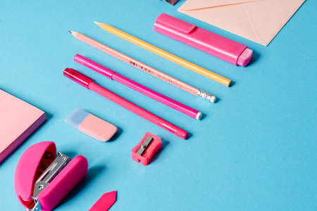 Close-up view of a set for writing consisting of: letter, marker, pen, pencil, eraser, stapler, paper lying in a blue studioの写真素材
