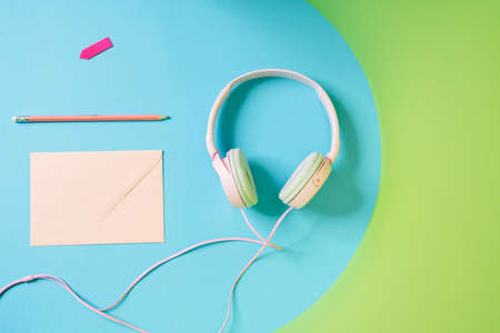Overhead view of a set of wired headphones, writing and a pencil lying in a studio
