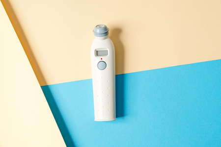 A close-up view of a thermometer for measuring body temperature lying on a colorful background in...