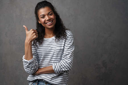 Happy young african woman in casual wear standing over gray backgroundの写真素材