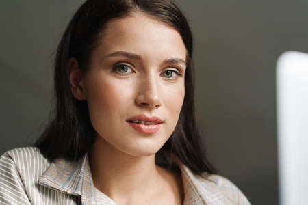 Close up of a young brunette white casual woman indoors looking at camera