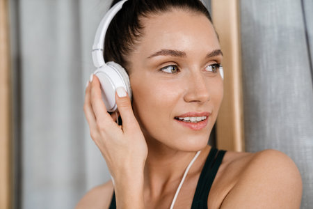 White brunette woman listening music with headphones at homeの写真素材