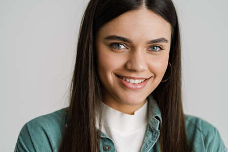 Young brunette woman smiling and looking at camera isolated over white backgroundの写真素材