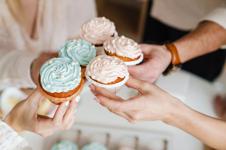 White friends holding muffins during gender reveal party indoorsの写真素材