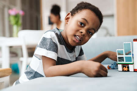 Black boy in t-shirt playing with toy on couch at homeの写真素材