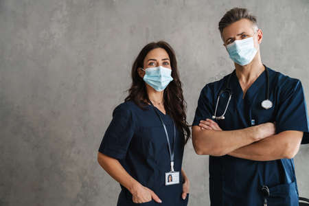 Two confident doctors in medical masks standing indoorsの写真素材