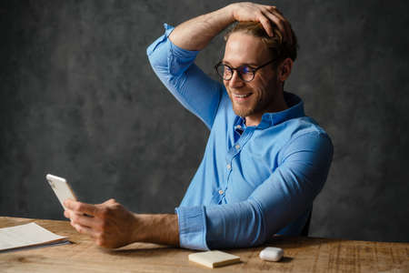 Smiling business man working with computer and mobile phoneの写真素材