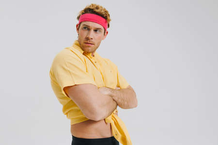 Young white gay man wearing headband standing over gray wall background arms foldedの写真素材