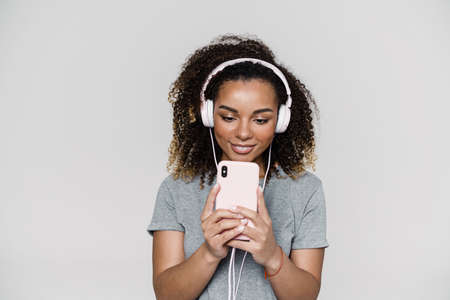 A black smiling woman in headphones making a photo while standing in the light studioの写真素材