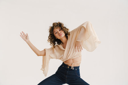 Young hispanic woman with curly hair dancing on camera isolated over white backgroundの写真素材