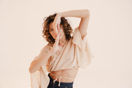 Young hispanic woman with curly hair dancing on camera isolated over white background