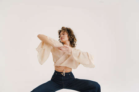 Young hispanic woman with curly hair dancing on camera isolated over white backgroundの写真素材