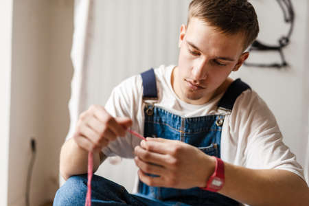 Young white man wearing overall working on craft rug at home