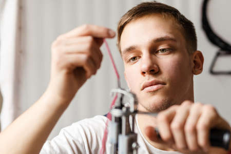 Young white man working with sewing machine indoors