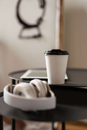 Close up of heasphones and takeaway cup on a table indoorsの写真素材