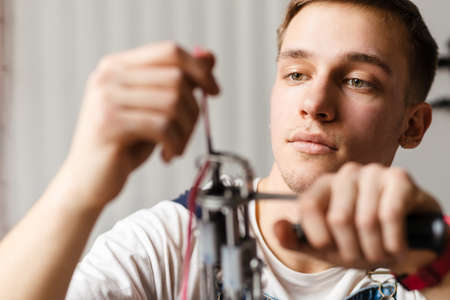Young white man working with sewing machine indoors